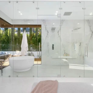 Spacious bathroom with a bathtub behind glass panels A spacious bathroom with a bathtub behind glass panels