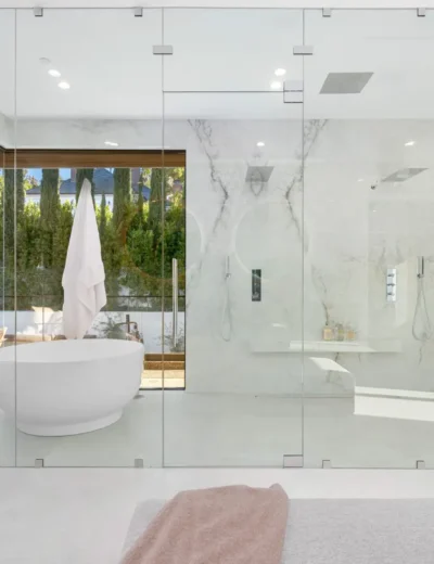 A spacious bathroom with a bathtub behind glass panels