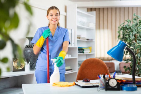 istockphoto-1350701180-612x612 Young woman in surgical scrubs cleaning floor. She's using mop and rubber gloves.